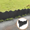 Black scalloped garden edging separating grass from a paved area. Produktbild-Vorschau