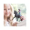 A young girl is holding a toy horse and rider. Voir les images du produit