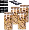 A set of four clear glass storage jars filled with cereal, topped with bamboo lids, and accompanied by a sheet of chalkboard labels and chalk. The jars are arranged in a staggered formation, with the front jars partially obscuring the back ones. Produktbild-Vorschau