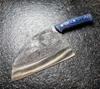 A cleaver knife with a blue and black patterned handle rests on a dark, textured surface. Anteprima dell’immagine prodotto