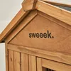 A close-up view of the top section of a wooden animal hutch, showing the roofline and a section of the front panel with text. Produktbild-Vorschau