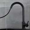 A black kitchen faucet with a pull-out spray head is shown against a gray tiled wall. Produktbild-Vorschau