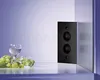 A black corner electrical outlet with two sockets is mounted on a wall, with a glass of white wine and a bunch of green grapes in the foreground. Produktbild-Vorschau