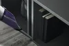 A handheld vacuum cleaner is being used to clean the edge of a shelf unit. Produktbild-Vorschau