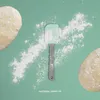 A baking scene with dough, flour, and a spatula on a teal background. Anteprima dell’immagine prodotto
