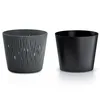 Two plant pots are shown side-by-side against a white background. The pot on the left is gray with a textured, wavy pattern and cutouts. The pot on the right is solid black. Voir les images du produit