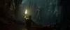 A person holding a torch in a dark cave with a statue in the background. Produktbild-Vorschau