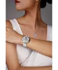 A woman wearing a white top, showing off a silver watch and necklace. Náhled obrázku produktu