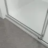 Close-up of the bottom track and glass edge of a shower enclosure, with a gray tiled floor in the foreground. Produktbild-Vorschau