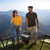 A couple is walking on a mountain path with a cooler. Anteprima dell’immagine prodotto
