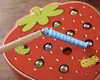 A close-up of a wooden strawberry-shaped toy with magnetic pieces. Voir les images du produit