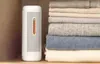 A white dehumidifier is placed on a shelf next to a stack of folded sweaters. Voir les images du produit
