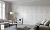 A modern living room with white paneled walls, a sofa, coffee table, and a floor lamp. Produktbild-Vorschau
