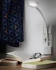 A white LED plug-in lamp is attached to a wall socket, illuminating an open book and a pair of glasses on a table. Produktbild-Vorschau