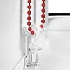 A close-up of a red beaded chain for a roller blind, attached to a clear plastic bracket. Produktbild-Vorschau