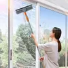 Frau reinigt mit grauem und orangem Teleskop-Fensterreiniger ein großes Glasfenster, mit sichtbarem Seifenschaum Produktbild-Vorschau