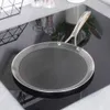 A griddle pan sits on a black induction stovetop, with kitchen accessories in the background. Voir les images du produit