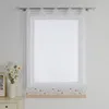 A white sheer curtain with a floral embroidered border hangs on a window. Produktbild-Vorschau