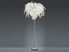 A floor lamp with a white, leaf-like shade on a silver stand, set against a plain gray background. Produktbild-Vorschau