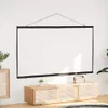 A white projection screen is hung on a white wall above a wooden cabinet with a small potted plant and a portable speaker on top. Podgląd zdjęcia produktu