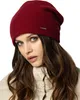 A woman wearing a burgundy beanie and a cream jacket. Produktbild-Vorschau