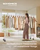 A woman is standing next to a clothing rack filled with clothes, organizing them. The scene is set in a well-lit room with a window in the background. Produktbild-Vorschau