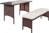 A brown rattan dining table with a glass top and a cream-cushioned bench are shown against a white background. Produktbild-Vorschau