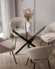 A round glass-top dining table with four cream-colored chairs is set up on a light wooden floor. Produktbild-Vorschau