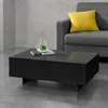 A black coffee table with a decorative terrarium and books on it, placed in front of a gray sofa with a yellow cushion. The background is a concrete wall. Anteprima dell’immagine prodotto