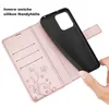 A hand is holding a black phone case, which is being inserted into a rose gold wallet-style phone case. The wallet case is open, revealing card slots and a decorative floral pattern. Produktbild-Vorschau