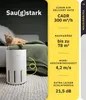 A white air purifier is shown in a living room setting with a cat lying on a blanket draped over a couch. Text overlays describe the product's features and specifications. Produktbild-Vorschau