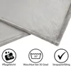 Close-up of a gray blanket with icons and text indicating care instructions. Produktbild-Vorschau
