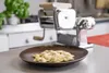 A pasta machine and a plate of ravioli are displayed on a kitchen counter. Voir les images du produit