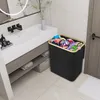 A laundry basket filled with clothes sits next to a bathroom vanity with a sink and mirror. Voir les images du produit