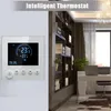 A smart thermostat is mounted on a wall next to a bookshelf filled with books and decorative items. A desk with a laptop is visible in the background. Podgląd zdjęcia produktu