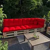 A red pallet sofa with cushions on a wooden deck, surrounded by greenery. Voir les images du produit