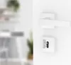 A white door handle and keyhole are shown on a white wall, with a blurred background of an interior space. Produktbild-Vorschau