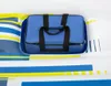A blue bag with black handles sits on a white surface with blue and yellow stripes. Produktbild-Vorschau