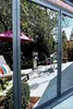 A reflection of a patio with furniture and plants in a large window. Produktbild-Vorschau