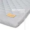 Close-up of a quilted mattress pad with a brand tag and text indicating its height. Náhľad obrázku produktu
