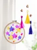 A handmade mobile with colorful stars inside an embroidery hoop, hanging in front of a white curtain. Anteprima dell’immagine prodotto
