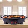 A black electric grill and hot pot combination with food cooking on it, placed on a wooden table in a kitchen setting. Produktbild-Vorschau