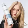 A woman holds a bottle of hair product in front of her blonde hair. Anteprima dell’immagine prodotto