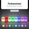 A row of seven penguin-shaped night lights, each illuminated in a different color, with color swatches below them. Produktbild-Vorschau