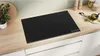 A black induction cooktop on a wooden countertop in a kitchen. Náhled obrázku produktu