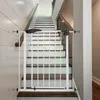A white metal safety gate is installed at the bottom of a staircase. Produktbild-Vorschau
