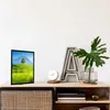 A framed picture of a landscape is displayed on a wooden shelf next to decorative items. Anteprima dell’immagine prodotto