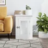 A white wooden cabinet with a glass door, placed next to a yellow sofa and a potted plant. Books are stacked on top of the cabinet. Náhled obrázku produktu