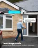 An older man carries a box towards a house with a security camera visible. Náhled obrázku produktu