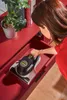 A woman is putting a vacuum cleaner into a red drawer. Produktbild-Vorschau